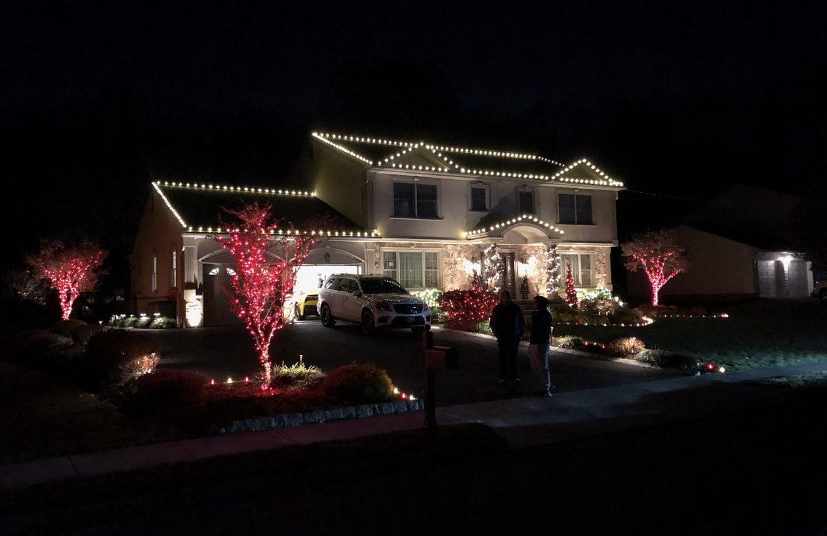 Two-story home with white rooflines and red bushes